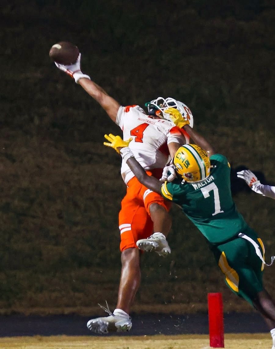 Jaxon Dollar fully extended for a one-handed catch over a defender at the goal line under the lights.