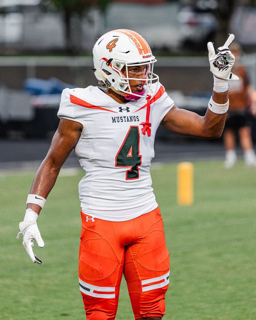Jaxon Dollar in the white East Lincoln Mustangs number 4 road uniform, helmet on, signalling with two fingers raised.