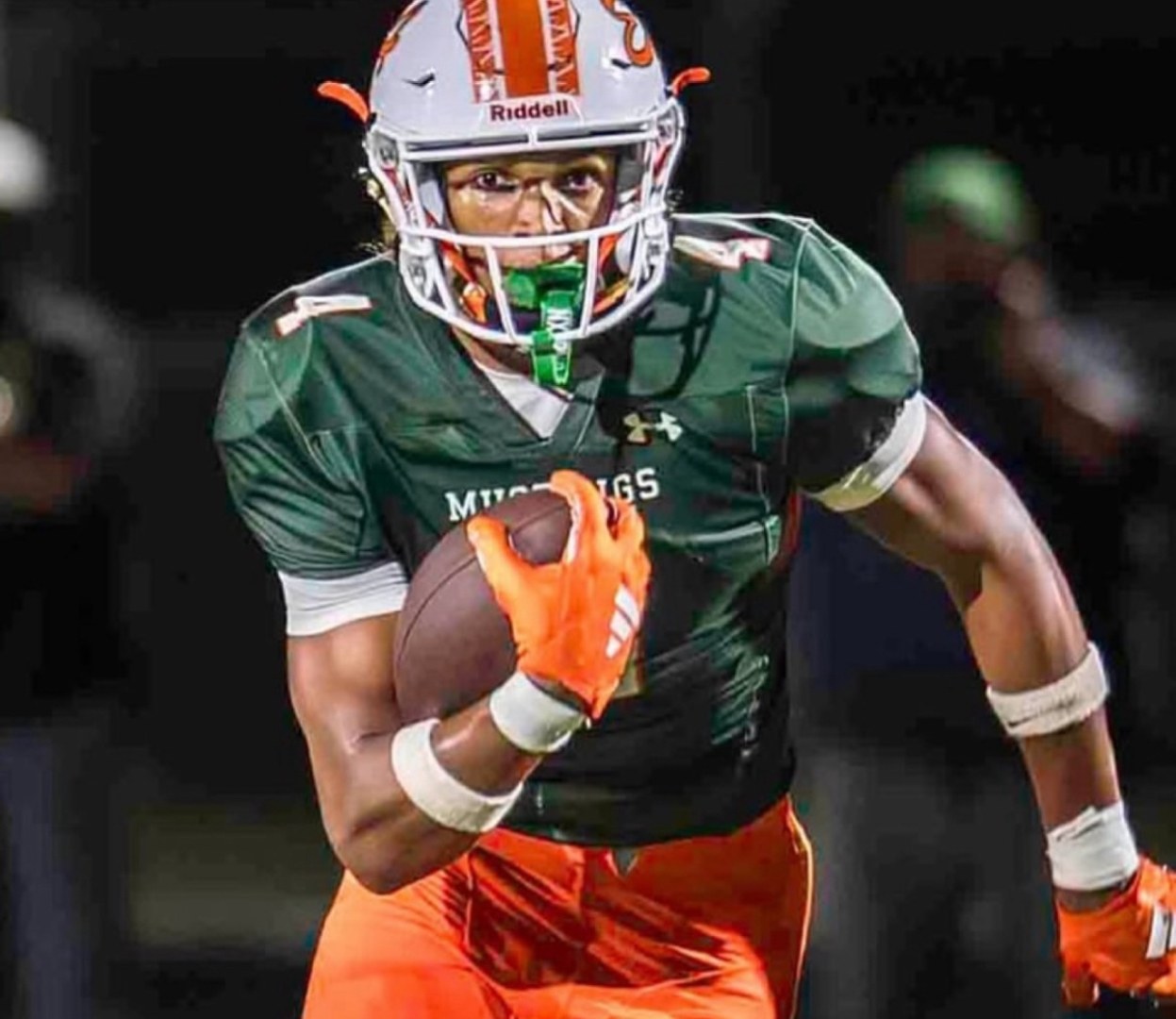 Jaxon Dollar tucking the ball and accelerating upfield in the green East Lincoln jersey.