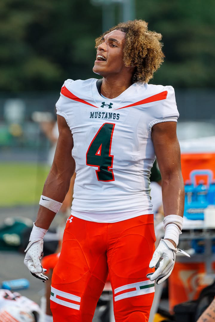Jaxon Dollar on the sideline with his helmet off, in the white East Lincoln Mustangs number 4 road uniform.